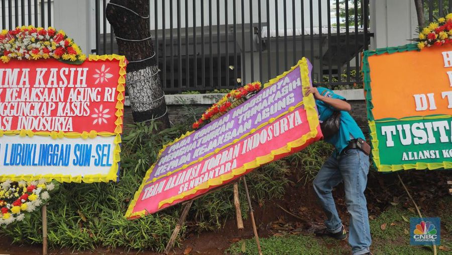Warga melihat karangan bunga dari nasabah korban Koperasi Simpan Pinjam (KSP) Indosurya yang dipasang disepanjang jalur pedestrian kawasan kejagung, Jakarta, Rabu (24/5/2023). (CNBC Indonesia/Muhammad Sabki)