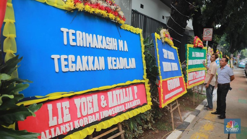 Warga melihat karangan bunga dari nasabah korban Koperasi Simpan Pinjam (KSP) Indosurya yang dipasang disepanjang jalur pedestrian kawasan kejagung, Jakarta, Rabu (24/5/2023). (CNBC Indonesia/Muhammad Sabki)