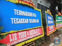Warga melihat karangan bunga dari nasabah korban Koperasi Simpan Pinjam (KSP) Indosurya yang dipasang di sepanjang pedestrian kawasan kompleks perkantoran Kejaksaan Agung, Jakarta Pusat, Rabu (24/5/2023). (CNBC Indonesia/Muhammad Sabki)