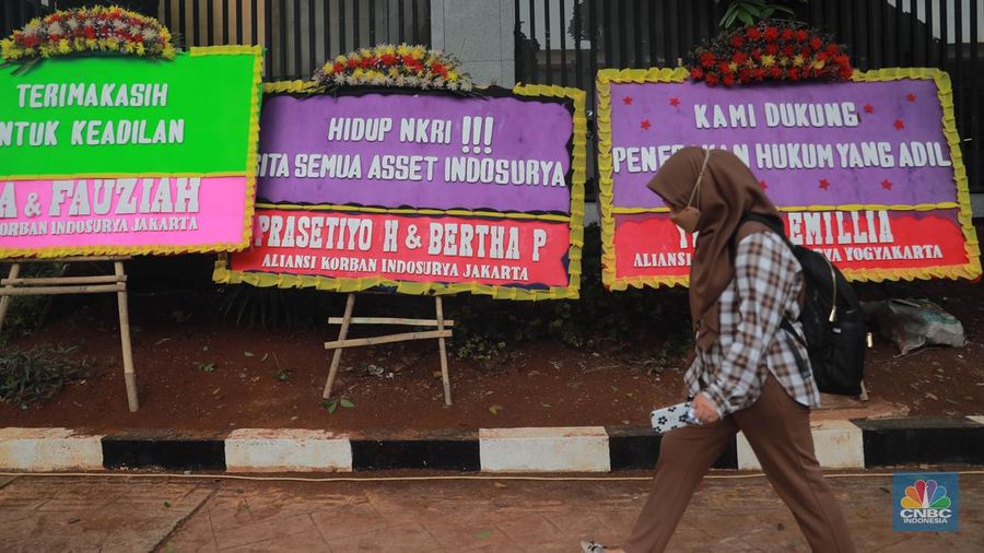 Warga melihat karangan bunga dari nasabah korban Koperasi Simpan Pinjam (KSP) Indosurya yang dipasang disepanjang jalur pedestrian kawasan kejagung, Jakarta, Rabu (24/5/2023). (CNBC Indonesia/Muhammad Sabki)
