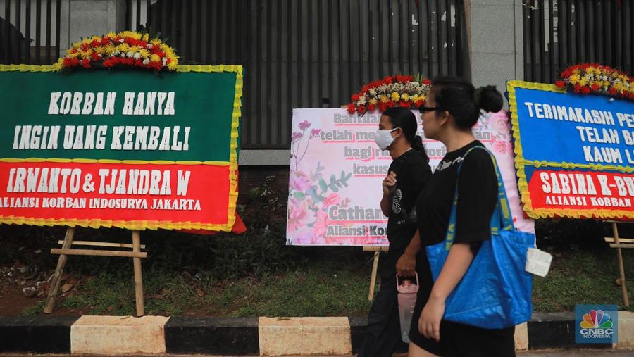 Warga melihat karangan bunga dari nasabah korban Koperasi Simpan Pinjam (KSP) Indosurya yang dipasang disepanjang jalur pedestrian kawasan kejagung, Jakarta, Rabu (24/5/2023). (CNBC Indonesia/Muhammad Sabki)