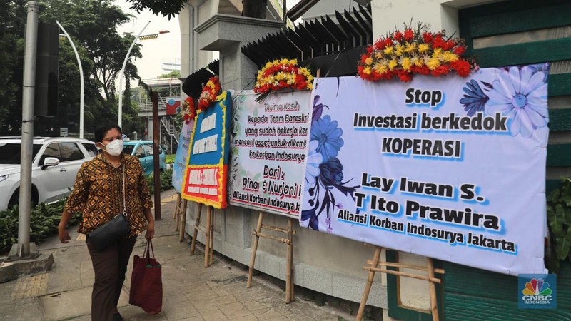 Warga melihat karangan bunga dari nasabah korban Koperasi Simpan Pinjam (KSP) Indosurya yang dipasang disepanjang jalur pedestrian kawasan kejagung, Jakarta, Rabu (24/5/2023). (CNBC Indonesia/Muhammad Sabki)