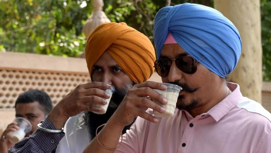 People drink Thandai, a traditional Indian drink prepared with milk, sugar and spices, on a hot summer day in Amritsar on May 24, 2023. (Photo by Narinder NANU / AFP) (Photo by NARINDER NANU/AFP via Getty Images)