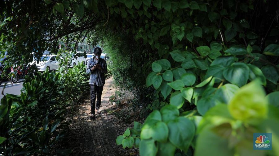 Pejalan kaki melintasi trototar yang tidak terawat di Jalan Asia Afrika, Senayan, Jakarta, Jumat (26/5/2023). (CNBC Indonesia/Faisal Rahman)