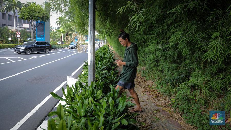 Pejalan kaki melintasi trototar yang tidak terawat di Jalan Asia Afrika, Senayan, Jakarta, Jumat (26/5/2023). (CNBC Indonesia/Faisal Rahman)