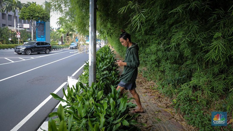 Pejalan kaki melintasi trototar yang tidak terawat di Jalan Asia Afrika, Senayan, Jakarta, Jumat (26/5/2023). (CNBC Indonesia/Faisal Rahman)