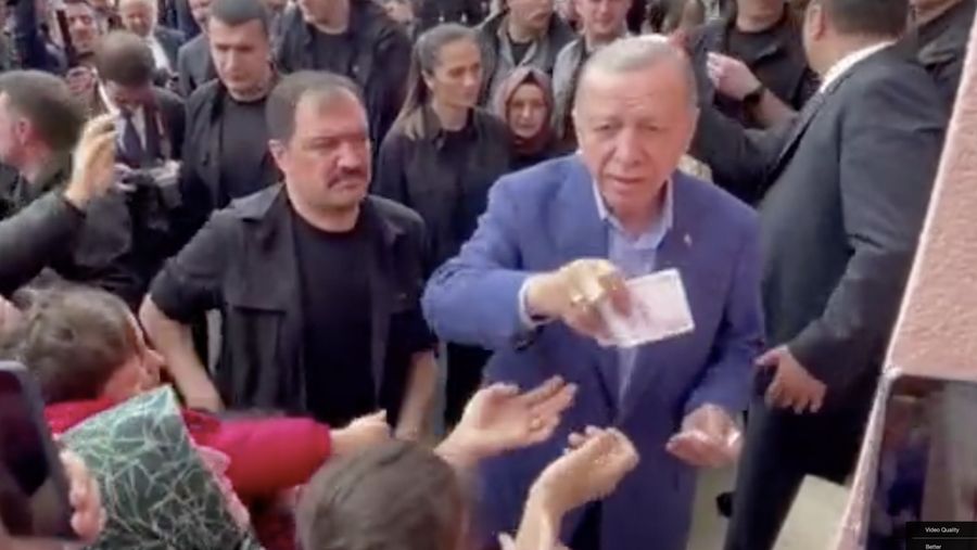 Presiden Turki Tayyip Erdogan membagikan uang kepada para pendukung yang berkumpul di luar TPS. (REUTERS)
