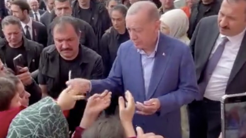 Presiden Turki Tayyip Erdogan membagikan uang kepada para pendukung yang berkumpul di luar TPS. (REUTERS)