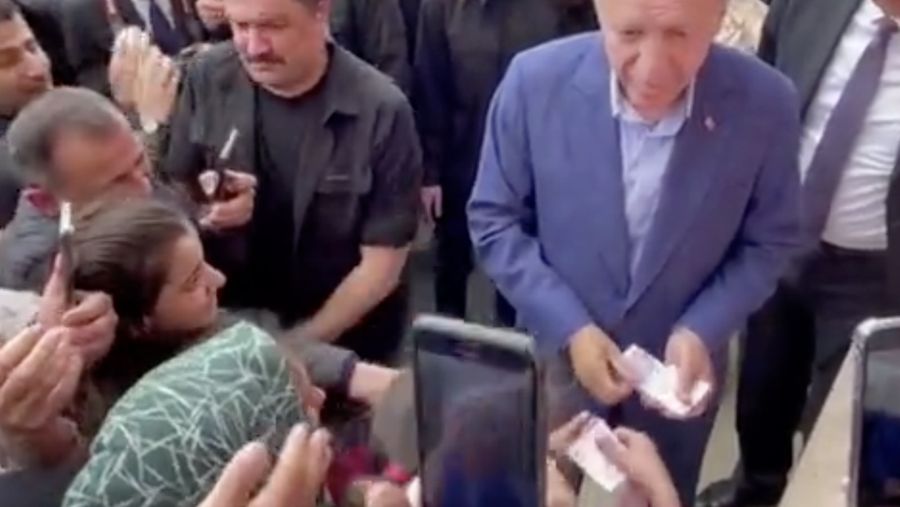 Presiden Turki Tayyip Erdogan membagikan uang kepada para pendukung yang berkumpul di luar TPS. (REUTERS)