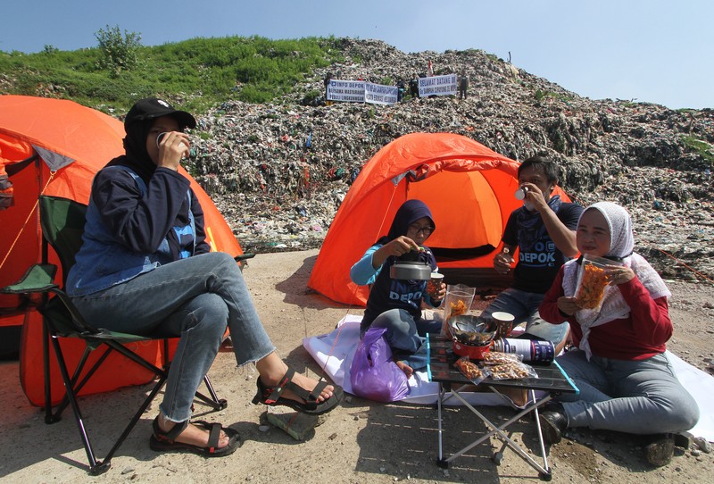 Beberapa aktivis lingkungan makan di dekat tenda mereka saat aksi damai di TPA Cipayung di Depok, Provinsi Jawa Barat Indonesia pada 31 Mei 2023. Beberapa aktivis lingkungan makan di dekat tenda mereka saat aksi damai di TPA Cipayung di Depok, Provinsi Jawa Barat Indonesia pada 31 Mei 2023. Aktivis lingkungan ambil bagian dalam aksi damai untuk menunjukkan meningkatnya penumpukan sampah yang melebihi kapasitas dan menyebabkan berbagai masalah kesehatan dan lingkungan di kota. (Eko Siswono Toyudho/Anadolu Agency via Getty Images)