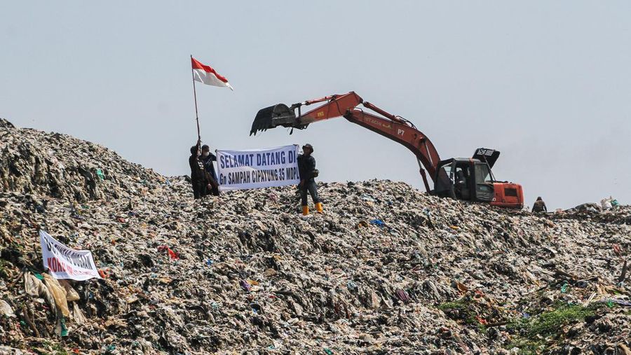 Beberapa aktivis lingkungan makan di dekat tenda mereka saat aksi damai di TPA Cipayung di Depok, Provinsi Jawa Barat Indonesia pada 31 Mei 2023. Aktivis lingkungan ambil bagian dalam aksi damai untuk menunjukkan meningkatnya penumpukan sampah yang melebihi kapasitas dan menyebabkan berbagai masalah kesehatan dan lingkungan di kota. (Eko Siswono Toyudho/Anadolu Agency via Getty Images)