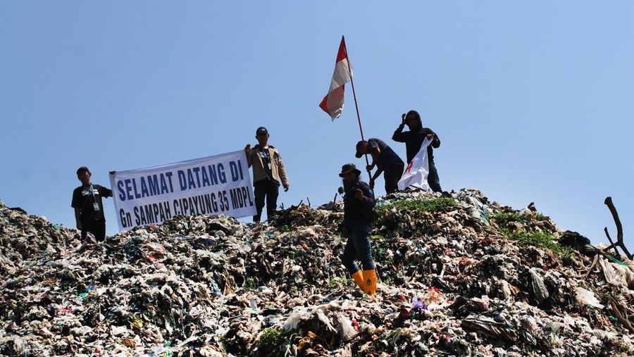 Beberapa aktivis lingkungan makan di dekat tenda mereka saat aksi damai di TPA Cipayung di Depok, Provinsi Jawa Barat Indonesia pada 31 Mei 2023. Aktivis lingkungan ambil bagian dalam aksi damai untuk menunjukkan meningkatnya penumpukan sampah yang melebihi kapasitas dan menyebabkan berbagai masalah kesehatan dan lingkungan di kota. (Eko Siswono Toyudho/Anadolu Agency via Getty Images)