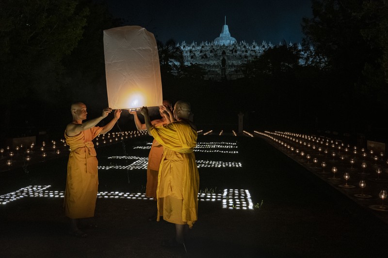Umat Buddha dan turis melepaskan lampion ke udara di Candi Borobudur saat perayaan Hari Raya Waisak pada 4 Juni 2023 di Magelang, Jawa Tengah, Indonesia. Waisak dirayakan selama bulan purnama di bulan Mei atau Juni dengan upacara yang berpusat di sekitar tiga candi Budha, peziarah berjalan dari Mendut ke Pawon, berakhir di Borobudur. Hari suci merayakan kelahiran, pencerahan ke nirwana, dan meninggalnya Buddha Gautama, pendiri agama Buddha. (Ulet Ifansasti/Getty Images)