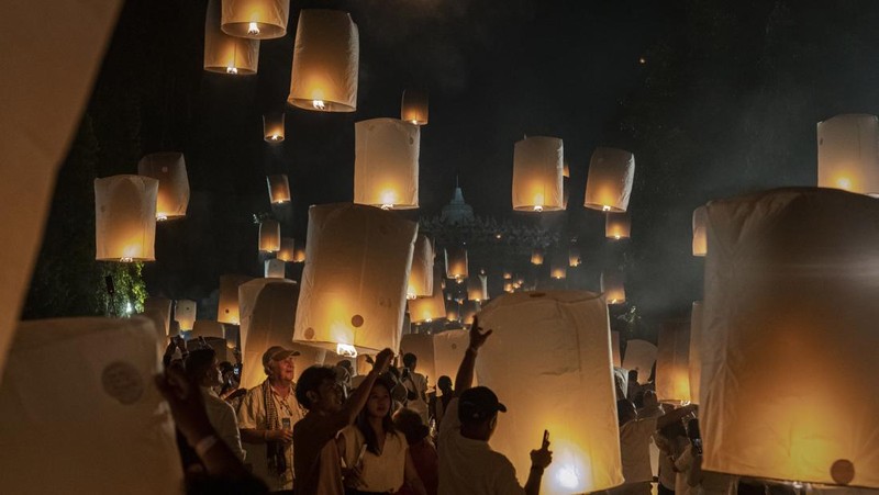 Umat Buddha dan turis melepaskan lampion ke udara di Candi Borobudur saat perayaan Hari Raya Waisak pada 4 Juni 2023 di Magelang, Jawa Tengah, Indonesia. Waisak dirayakan selama bulan purnama di bulan Mei atau Juni dengan upacara yang berpusat di sekitar tiga candi Budha, peziarah berjalan dari Mendut ke Pawon, berakhir di Borobudur. Hari suci merayakan kelahiran, pencerahan ke nirwana, dan meninggalnya Buddha Gautama, pendiri agama Buddha. (Ulet Ifansasti/Getty Images)