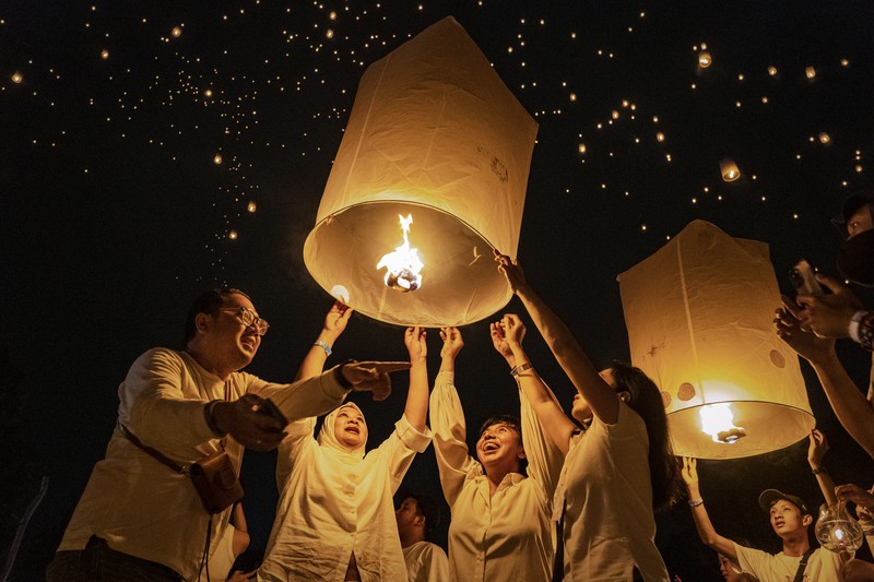 Umat Buddha dan turis melepaskan lampion ke udara di Candi Borobudur saat perayaan Hari Raya Waisak pada 4 Juni 2023 di Magelang, Jawa Tengah, Indonesia. Waisak dirayakan selama bulan purnama di bulan Mei atau Juni dengan upacara yang berpusat di sekitar tiga candi Budha, peziarah berjalan dari Mendut ke Pawon, berakhir di Borobudur. Hari suci merayakan kelahiran, pencerahan ke nirwana, dan meninggalnya Buddha Gautama, pendiri agama Buddha. (Ulet Ifansasti/Getty Images)