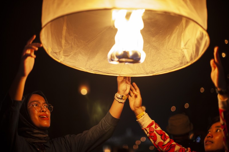 Umat Buddha dan turis melepaskan lampion ke udara di Candi Borobudur saat perayaan Hari Raya Waisak pada 4 Juni 2023 di Magelang, Jawa Tengah, Indonesia. Waisak dirayakan selama bulan purnama di bulan Mei atau Juni dengan upacara yang berpusat di sekitar tiga candi Budha, peziarah berjalan dari Mendut ke Pawon, berakhir di Borobudur. Hari suci merayakan kelahiran, pencerahan ke nirwana, dan meninggalnya Buddha Gautama, pendiri agama Buddha. (Ulet Ifansasti/Getty Images)
