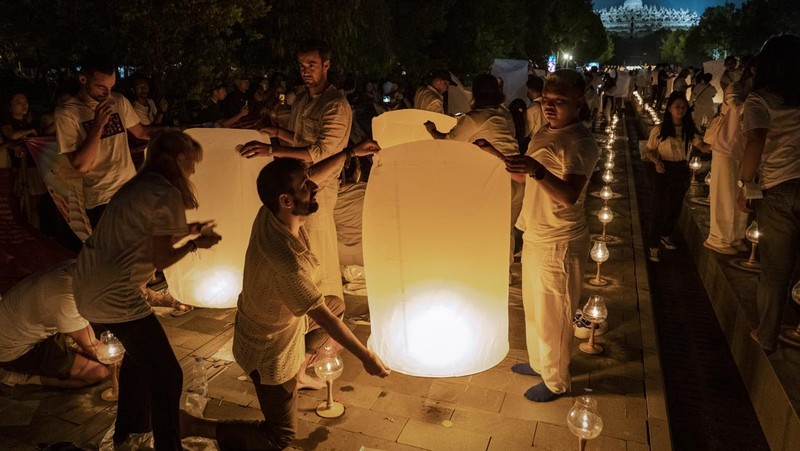 Umat Buddha dan turis melepaskan lampion ke udara di Candi Borobudur saat perayaan Hari Raya Waisak pada 4 Juni 2023 di Magelang, Jawa Tengah, Indonesia. Waisak dirayakan selama bulan purnama di bulan Mei atau Juni dengan upacara yang berpusat di sekitar tiga candi Budha, peziarah berjalan dari Mendut ke Pawon, berakhir di Borobudur. Hari suci merayakan kelahiran, pencerahan ke nirwana, dan meninggalnya Buddha Gautama, pendiri agama Buddha. (Ulet Ifansasti/Getty Images)