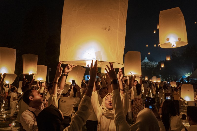 Umat Buddha dan turis melepaskan lampion ke udara di Candi Borobudur saat perayaan Hari Raya Waisak pada 4 Juni 2023 di Magelang, Jawa Tengah, Indonesia. Waisak dirayakan selama bulan purnama di bulan Mei atau Juni dengan upacara yang berpusat di sekitar tiga candi Budha, peziarah berjalan dari Mendut ke Pawon, berakhir di Borobudur. Hari suci merayakan kelahiran, pencerahan ke nirwana, dan meninggalnya Buddha Gautama, pendiri agama Buddha. (Ulet Ifansasti/Getty Images)
