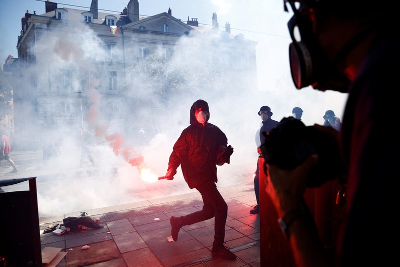 A masked prostester holds a red flare during clashes at a demonstration as part of the 14th day of nationwide protests against French government's pension reform law, in Nantes, France, June 6, 2023.  REUTERS/Stephane Mahe