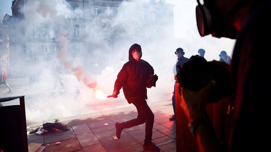 A masked prostester holds a red flare during clashes at a demonstration as part of the 14th day of nationwide protests against French government's pension reform law, in Nantes, France, June 6, 2023.  REUTERS/Stephane Mahe