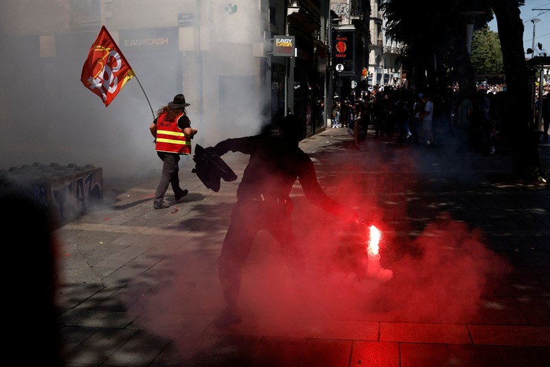 A masked prostester holds a red flare during clashes at a demonstration as part of the 14th day of nationwide protests against French government's pension reform law, in Nantes, France, June 6, 2023.  REUTERS/Stephane Mahe