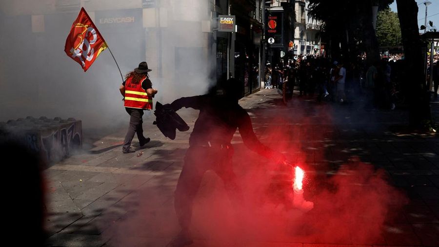 A masked prostester holds a red flare during clashes at a demonstration as part of the 14th day of nationwide protests against French government's pension reform law, in Nantes, France, June 6, 2023.  REUTERS/Stephane Mahe