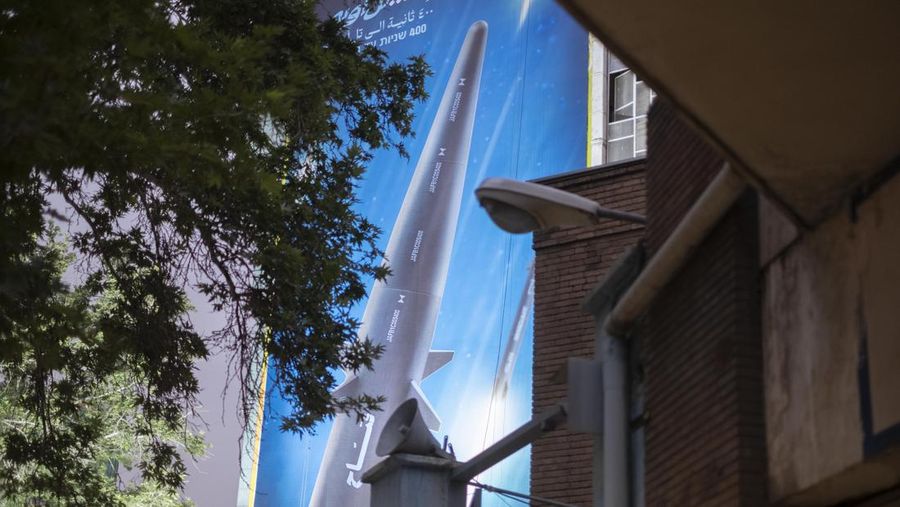 An Iranian couple walk past a giant image of Fattah, Iran's first-ever hypersonic missile, in Palestine square in downtown Tehran, June 7, 2023. According to Iran's state media, the Fattah solid fuel hypersonic missile can reach Tel Aviv in 400 seconds from inside Iran and travels at a speed of 5,145 meters per second.  (Photo by Morteza Nikoubazl/NurPhoto via Getty Images)