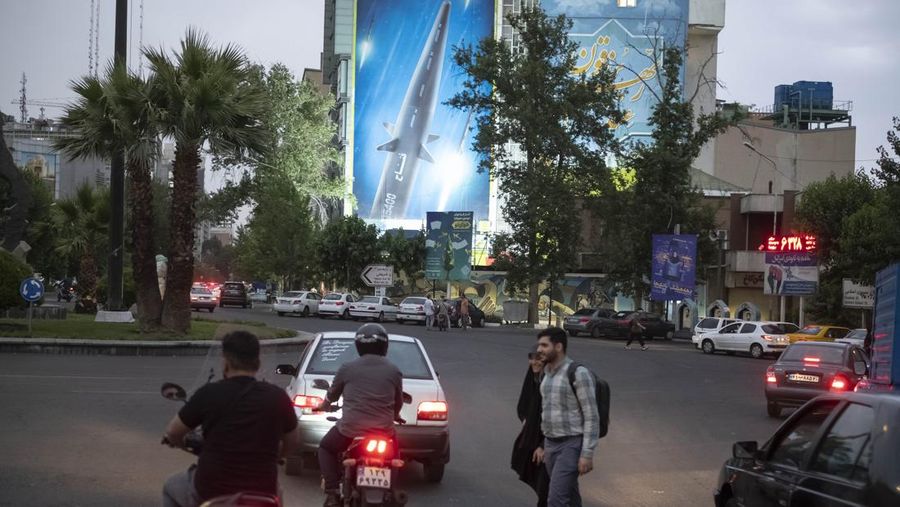 An Iranian couple walk past a giant image of Fattah, Iran's first-ever hypersonic missile, in Palestine square in downtown Tehran, June 7, 2023. According to Iran's state media, the Fattah solid fuel hypersonic missile can reach Tel Aviv in 400 seconds from inside Iran and travels at a speed of 5,145 meters per second.  (Photo by Morteza Nikoubazl/NurPhoto via Getty Images)
