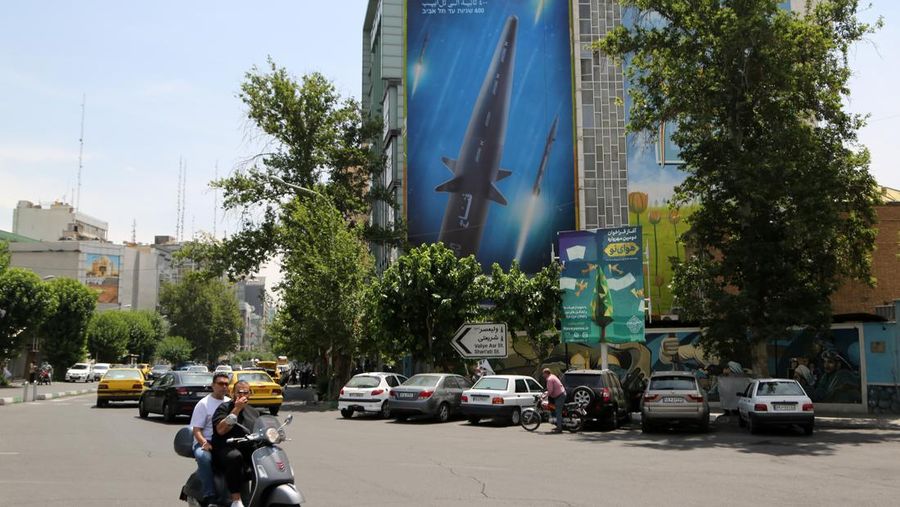 An Iranian couple walk past a giant image of Fattah, Iran's first-ever hypersonic missile, in Palestine square in downtown Tehran, June 7, 2023. According to Iran's state media, the Fattah solid fuel hypersonic missile can reach Tel Aviv in 400 seconds from inside Iran and travels at a speed of 5,145 meters per second.  (Photo by Morteza Nikoubazl/NurPhoto via Getty Images)