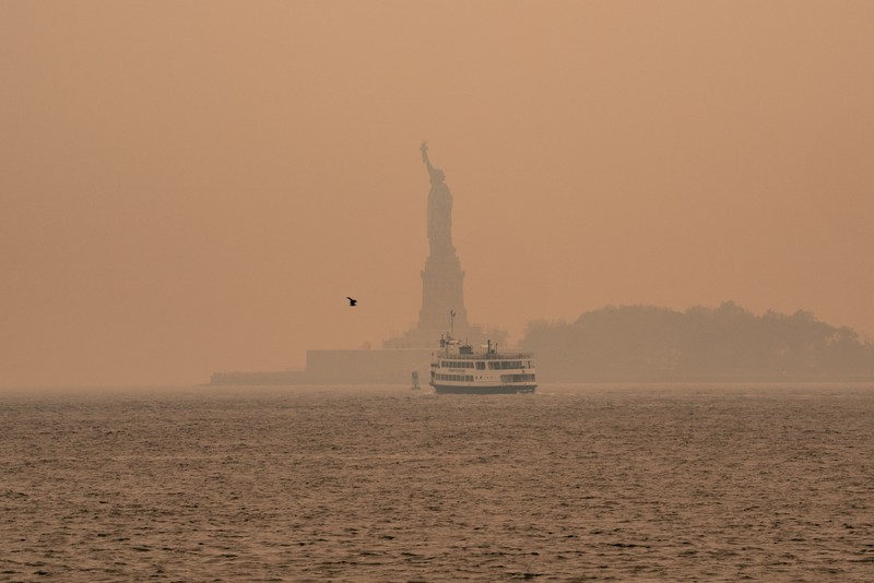 Kabut berasap dari kebakaran hutan di Kanada menyelimuti Patung Liberty di Upper Bay pada 7 Juni 2023 di New York City. New York menduduki puncak daftar kota besar paling tercemar di dunia pada Selasa malam, karena asap dari kebakaran terus menyelimuti Pantai Timur. (David Dee Delgado/Getty Images)