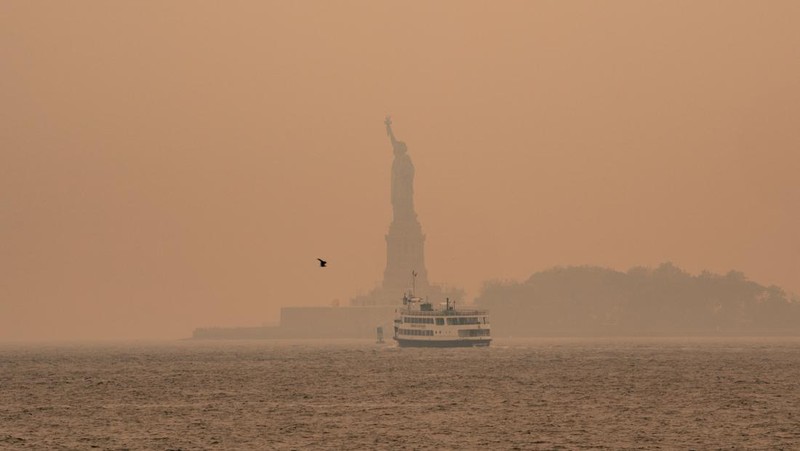 Kabut berasap dari kebakaran hutan di Kanada menyelimuti Patung Liberty di Upper Bay pada 7 Juni 2023 di New York City. New York menduduki puncak daftar kota besar paling tercemar di dunia pada Selasa malam, karena asap dari kebakaran terus menyelimuti Pantai Timur. (David Dee Delgado/Getty Images)