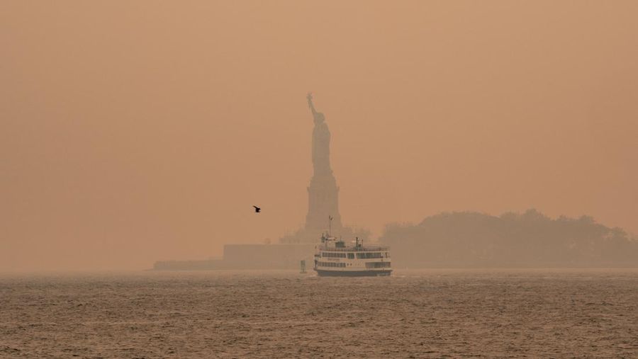 Kabut berasap dari kebakaran hutan di Kanada menyelimuti Patung Liberty di Upper Bay pada 7 Juni 2023 di New York City. New York menduduki puncak daftar kota besar paling tercemar di dunia pada Selasa malam, karena asap dari kebakaran terus menyelimuti Pantai Timur. (David Dee Delgado/Getty Images)