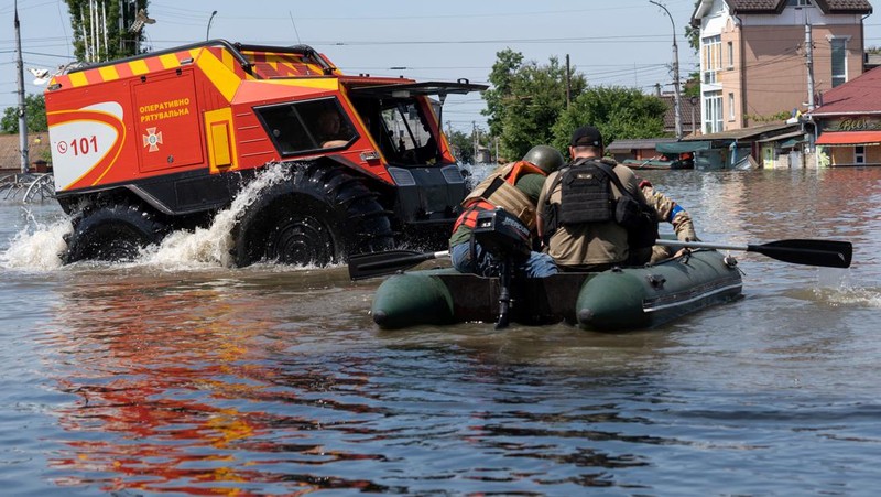 Tim penyelamat mengevakuasi seorang wanita dengan anjingnya di daerah banjir kota pada 7 Juni 2023 di Kherson, Ukraina. Akibat rusaknya bendungan Kakhovka, sekitar 80 pemukiman, termasuk Kherson, terancam banjir. Pihak berwenang dan sukarelawan mulai mengevakuasi penduduk dari daerah berbahaya. (Yan Dobronosov/Global Images Ukraine via Getty Images)