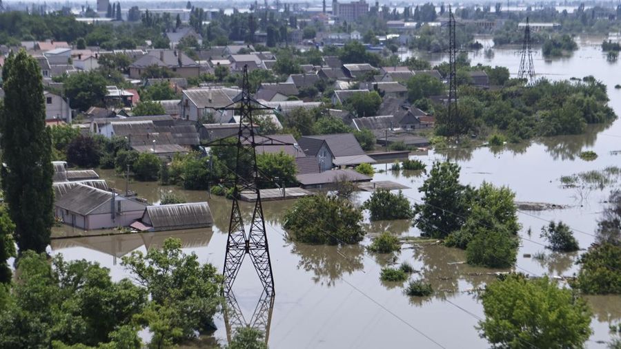 Tim penyelamat mengevakuasi seorang wanita dengan anjingnya di daerah banjir kota pada 7 Juni 2023 di Kherson, Ukraina. Akibat rusaknya bendungan Kakhovka, sekitar 80 pemukiman, termasuk Kherson, terancam banjir. Pihak berwenang dan sukarelawan mulai mengevakuasi penduduk dari daerah berbahaya. (Yan Dobronosov/Global Images Ukraine via Getty Images)