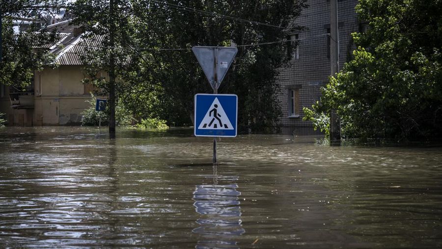 Tim penyelamat mengevakuasi seorang wanita dengan anjingnya di daerah banjir kota pada 7 Juni 2023 di Kherson, Ukraina. Akibat rusaknya bendungan Kakhovka, sekitar 80 pemukiman, termasuk Kherson, terancam banjir. Pihak berwenang dan sukarelawan mulai mengevakuasi penduduk dari daerah berbahaya. (Yan Dobronosov/Global Images Ukraine via Getty Images)