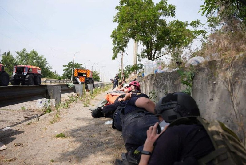 Emergency workers lay down during a Russian military strike while they evacuate people from a flooded area after the Nova Kakhovka dam breached, amid Russia's attack on Ukraine, during a Russian military strike in Kherson, Ukraine June 8, 2023. Ukrainian Presidential Press Service/Handout via REUTERS ATTENTION EDITORS - THIS IMAGE HAS BEEN SUPPLIED BY A THIRD PARTY.