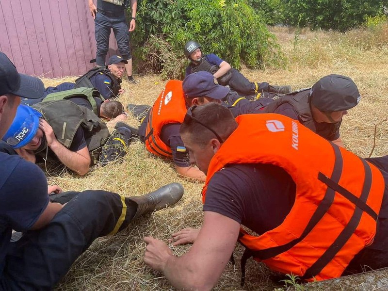 Emergency workers lay down during a Russian military strike while they evacuate people from a flooded area after the Nova Kakhovka dam breached, amid Russia's attack on Ukraine, during a Russian military strike in Kherson, Ukraine June 8, 2023. Ukrainian Presidential Press Service/Handout via REUTERS ATTENTION EDITORS - THIS IMAGE HAS BEEN SUPPLIED BY A THIRD PARTY.