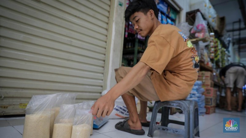 Pedagang menimbang dan mengemas gula pasir di Pasar Rumput, Jakarta, Jumat (9/6/2023). Harga gula pasir di Pasar Rumput rata-rata dijual dengan harga Rp15 ribu per kilogram. (CNBC Indonesia/Faisal Rahman)