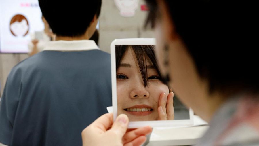 A student practices smiling with a mirror at a smile training course at Sokei Art School in Tokyo, Japan, May 30, 2023. REUTERS/Kim Kyung-Hoon