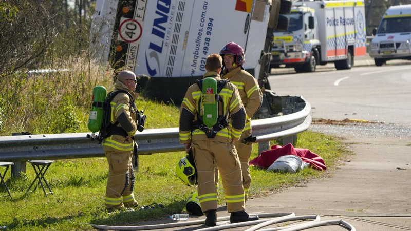 Polisi memeriksa sebuah bus di sisinya dekat kota Greta setelah kecelakaan di Hunter Valley, utara Sydney, Australia, Senin, 12 Juni 2023. Bus yang membawa tamu pernikahan terguling pada malam berkabut di negara penghasil anggur Australia, menewaskan dan melukai banyak orang, kata polisi. (AP Photo/Mark Baker)