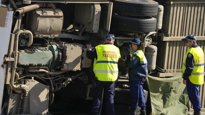 Polisi memeriksa sebuah bus di sisinya dekat kota Greta setelah kecelakaan di Hunter Valley, utara Sydney, Australia, Senin, 12 Juni 2023. Bus yang membawa tamu pernikahan terguling pada malam berkabut di negara penghasil anggur Australia, menewaskan dan melukai banyak orang, kata polisi. (AP Photo/Mark Baker)