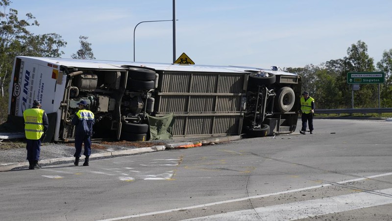 Polisi memeriksa sebuah bus di sisinya dekat kota Greta setelah kecelakaan di Hunter Valley, utara Sydney, Australia, Senin, 12 Juni 2023. Bus yang membawa tamu pernikahan terguling pada malam berkabut di negara penghasil anggur Australia, menewaskan dan melukai banyak orang, kata polisi. (AP Photo/Mark Baker)