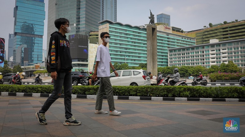 Warga berjalan melintasi Trotoar di kawasan Jalan M.H. Thamrin, Jakarta, Selasa (13/6/2023). Pemerintah resmi mengeluarkan aturan bebas masker pada ruang publik dan transportasi umum. (CNBC Indonesia/Faisal Rahman)