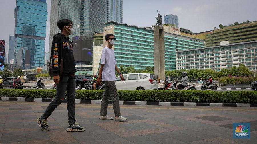Warga berjalan melintasi Trotoar di kawasan Jalan M.H. Thamrin, Jakarta, Selasa (13/6/2023). Pemerintah resmi mengeluarkan aturan bebas masker pada ruang publik dan transportasi umum. (CNBC Indonesia/Faisal Rahman)