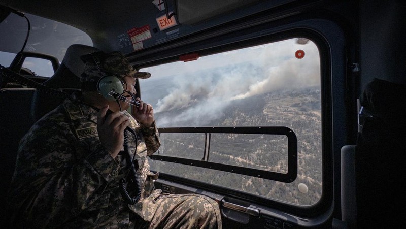 Sebuah helikopter terbang di tengah asap di atas sabuk hutan selama operasi untuk menahan kebakaran hutan di wilayah Abai timur, Kazakhstan, 12 Juni 2023. (REUTERS/Turar Kazangapov)