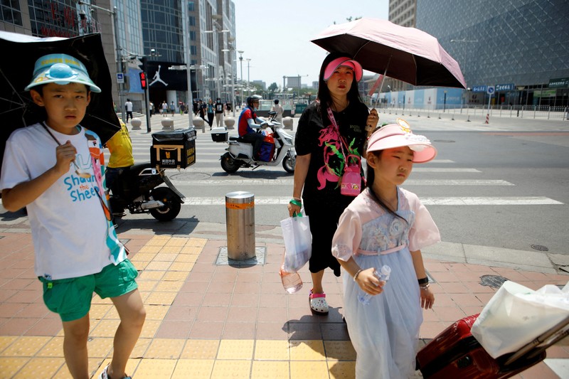 Seorang pejalan kaki melindungi dirinya dari sinar matahari saat melintasi jalan di hari yang panas di tengah peringatan oranye untuk gelombang panas, di Beijing, China 16 Juni 2023. Seorang pejalan kaki melindungi dirinya dari sinar matahari saat melintasi jalan di hari yang panas di tengah peringatan oranye untuk gelombang panas, di Beijing, China 16 Juni 2023. (REUTERS/Florence Lo)