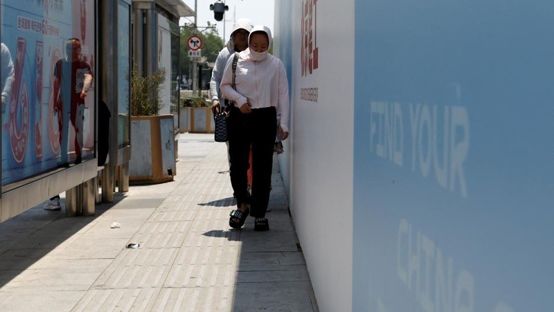 Seorang pejalan kaki melindungi dirinya dari sinar matahari saat melintasi jalan di hari yang panas di tengah peringatan oranye untuk gelombang panas, di Beijing, China 16 Juni 2023. (REUTERS/Florence Lo)