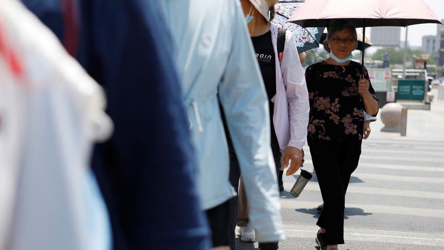 Seorang pejalan kaki melindungi dirinya dari sinar matahari saat melintasi jalan di hari yang panas di tengah peringatan oranye untuk gelombang panas, di Beijing, China 16 Juni 2023. (REUTERS/Florence Lo)