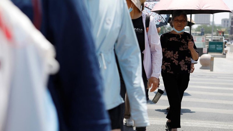 Seorang pejalan kaki melindungi dirinya dari sinar matahari saat melintasi jalan di hari yang panas di tengah peringatan oranye untuk gelombang panas, di Beijing, China 16 Juni 2023. (REUTERS/Florence Lo)