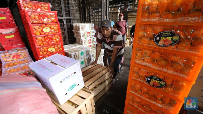 Pekerja melakukan bongkar muat buah impor dari China yang akan dipasarkan di Pasar Induk Kramat Jati, Jakarta, Senin (19/6/2023). (CNBC Indonesia/Tri Susilo)